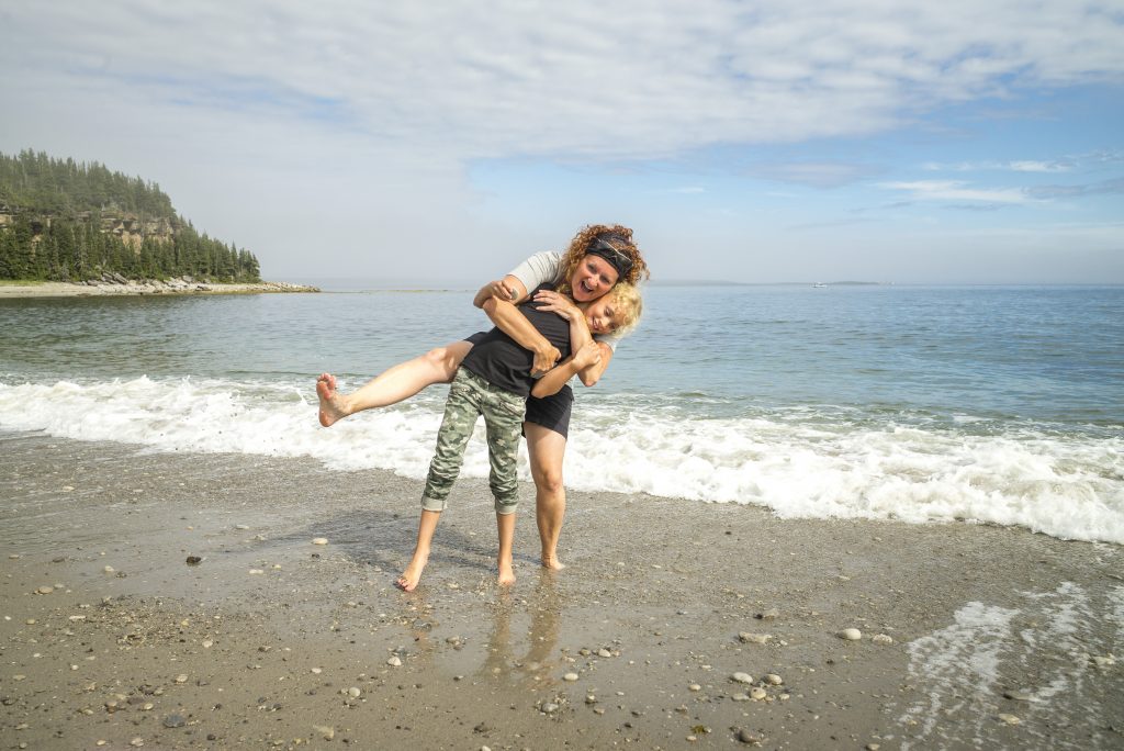 Une mère serre son enfant sur le littoral de calcaire de l’île du Havre. Réserve de parc national de l’Archipel-de-Mingan / A mother hugging her child on the limestone coastline of Île du Havre. Mingan Archipelago National Park Reserve